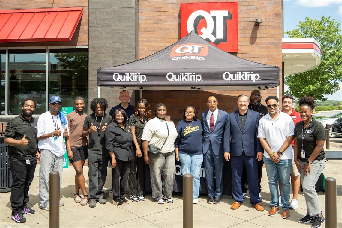 A smiling group of students in front of a Quiktrip
