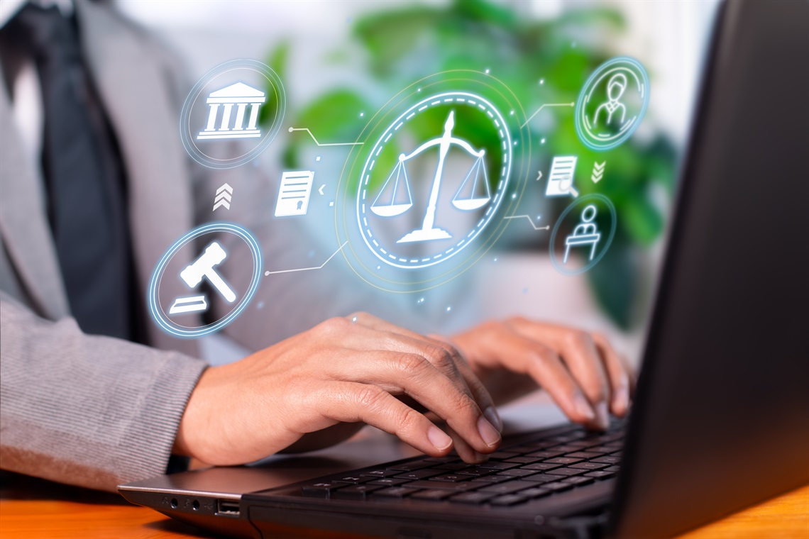 Person typing on a laptop with legal symbols projecting from the screen.