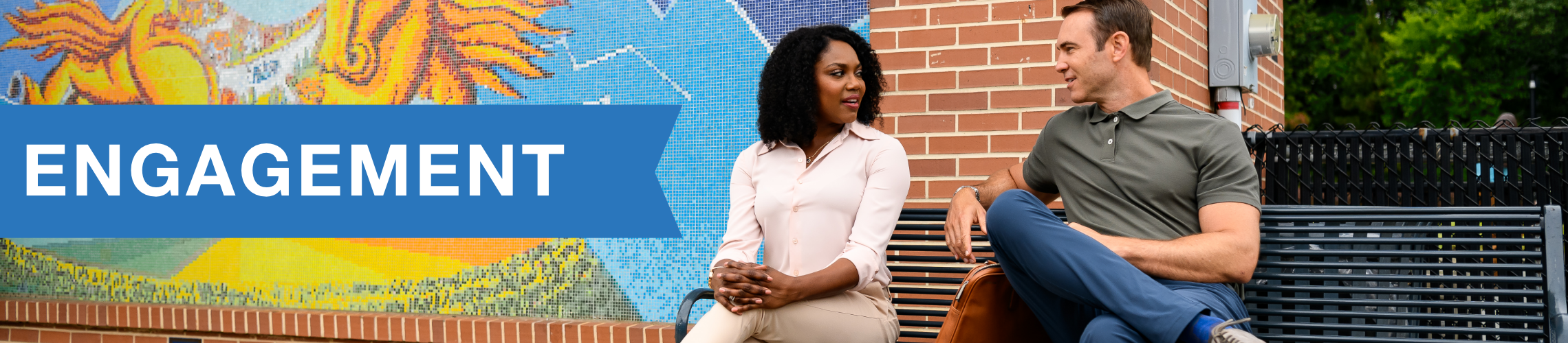 Two charlotte residents sitting on a metal bench, talking to each other