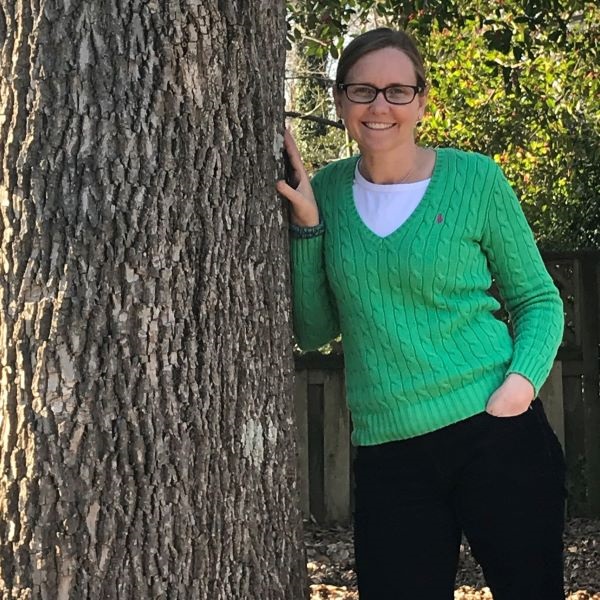 City Arborist Laurie Reid leaning against a large tree