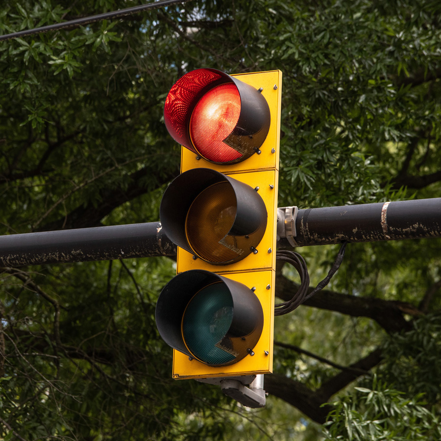 a traffic light with the red light illuminated and trees in the background