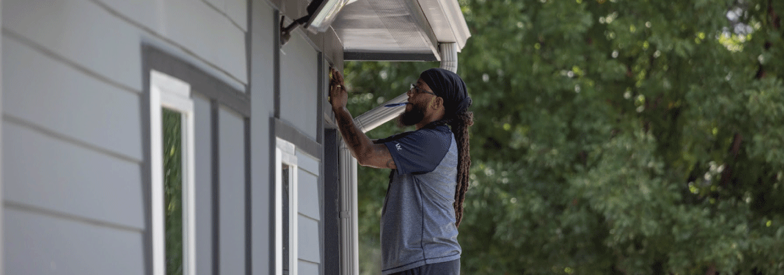 a person on a ladder working on a house in mid morning