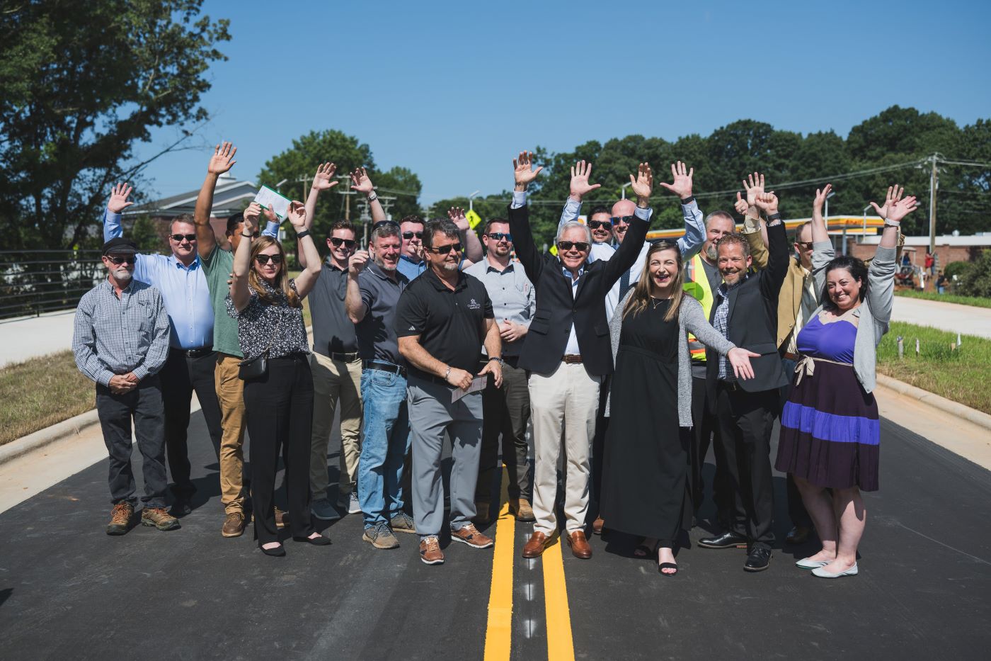 a large group of people standing in the middle of a roadway cheering