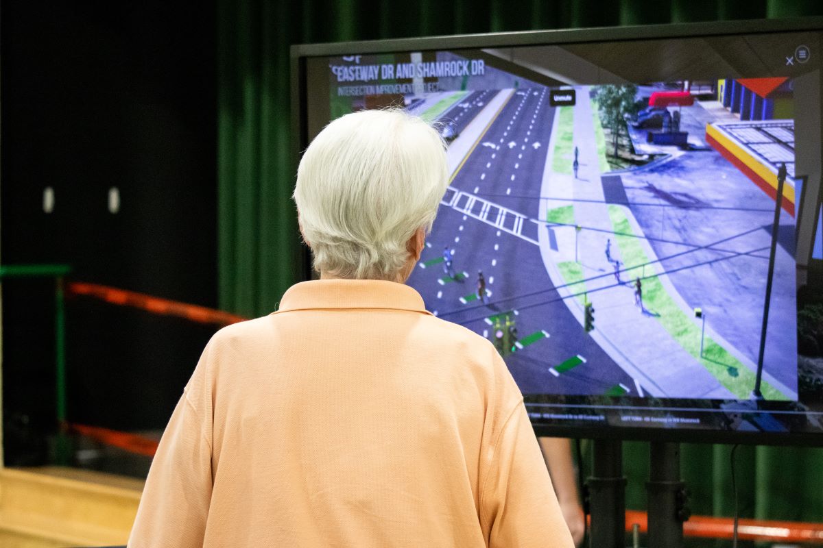 an older woman views a virtual simulation of street improvements during a municipal public meeting