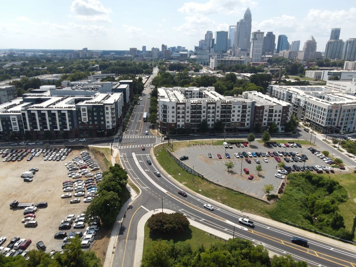 an aerial image of a newly re-paved street surrounded by parking lots and buildings with a city skyline in the distance