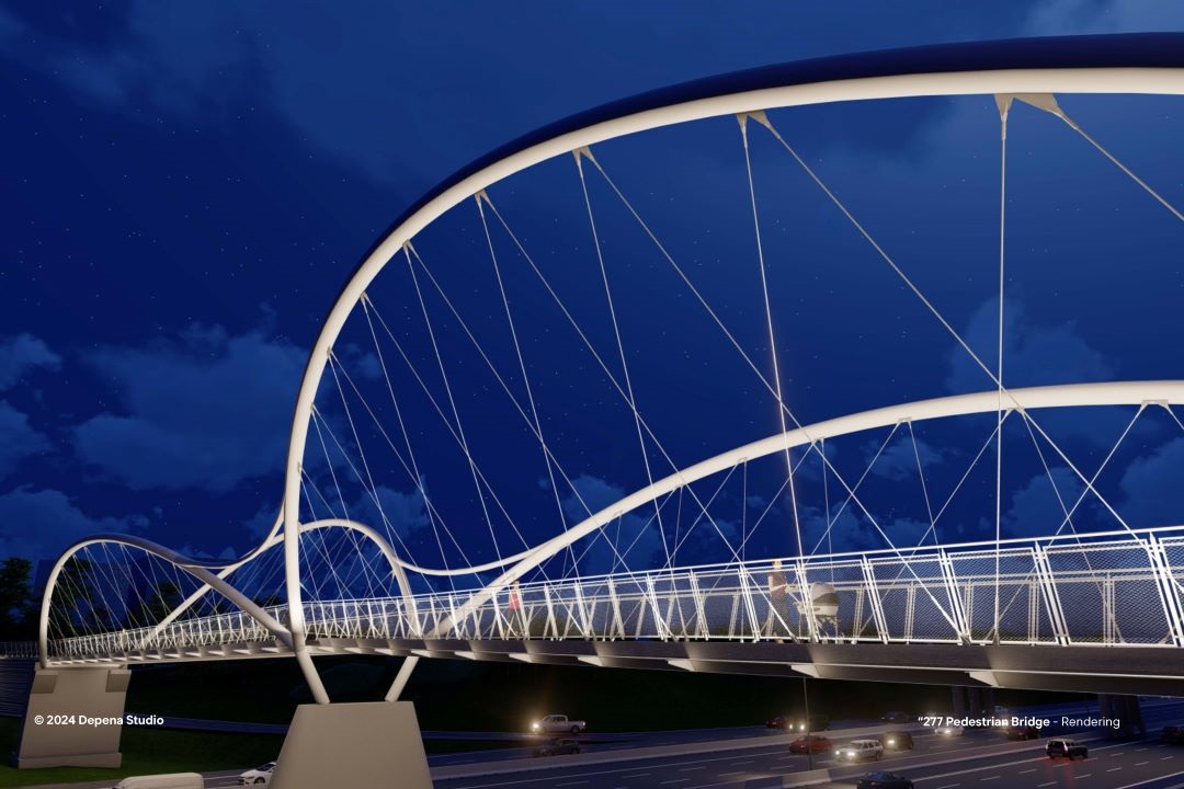 nighttime view of bridge from a distance, showing lit undulating spans with the roadway underneath