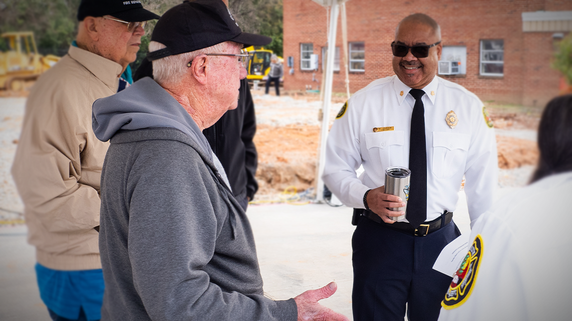 At the groundbreaking of the new Firehouse 11, Bob Summey shares memories with Charlotte Fire Chief Reginald Johnson.