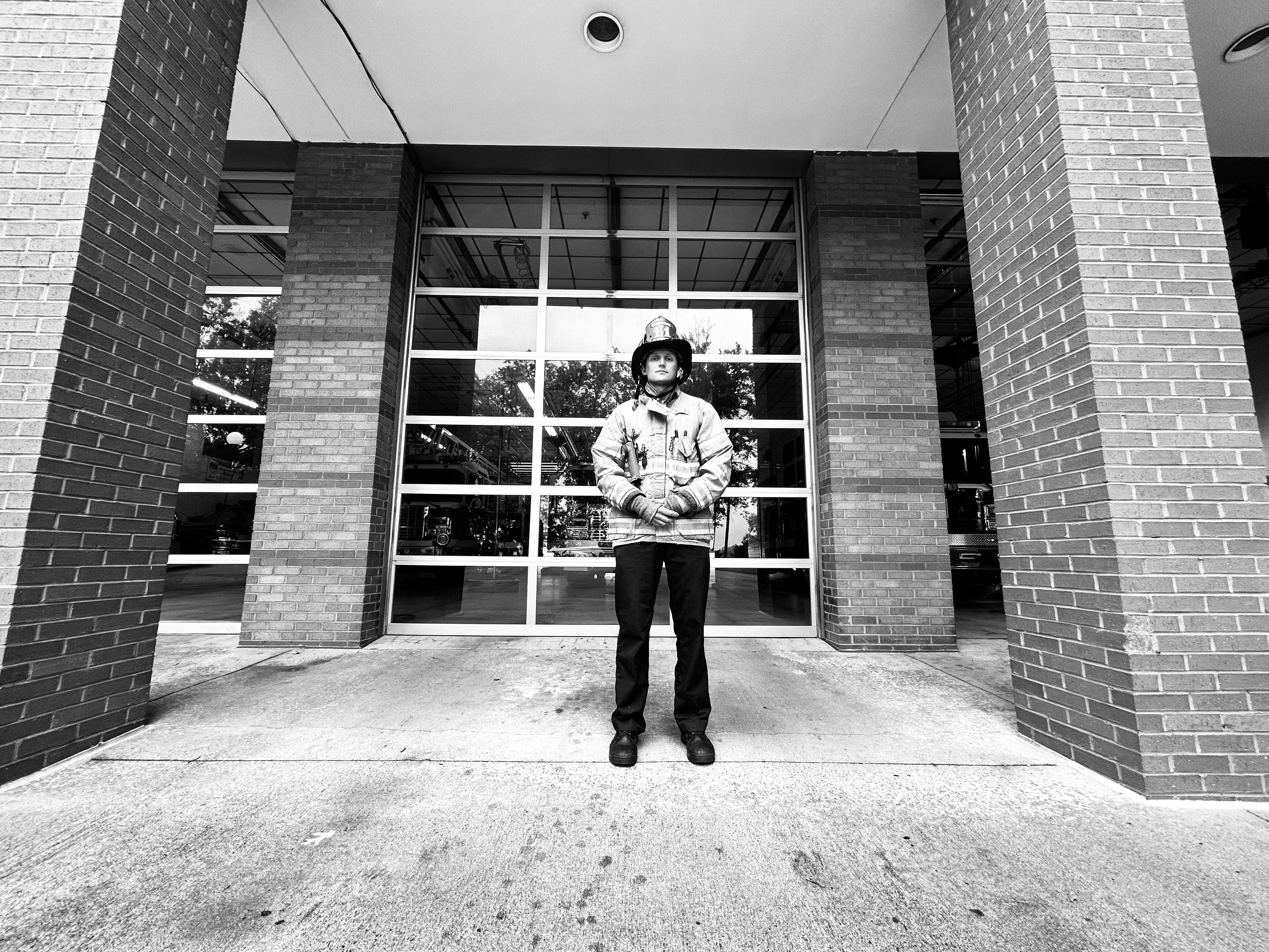 A black-and-white portrait of Watts in front of his firehouse captures the timeless tradition of service that drives him. 