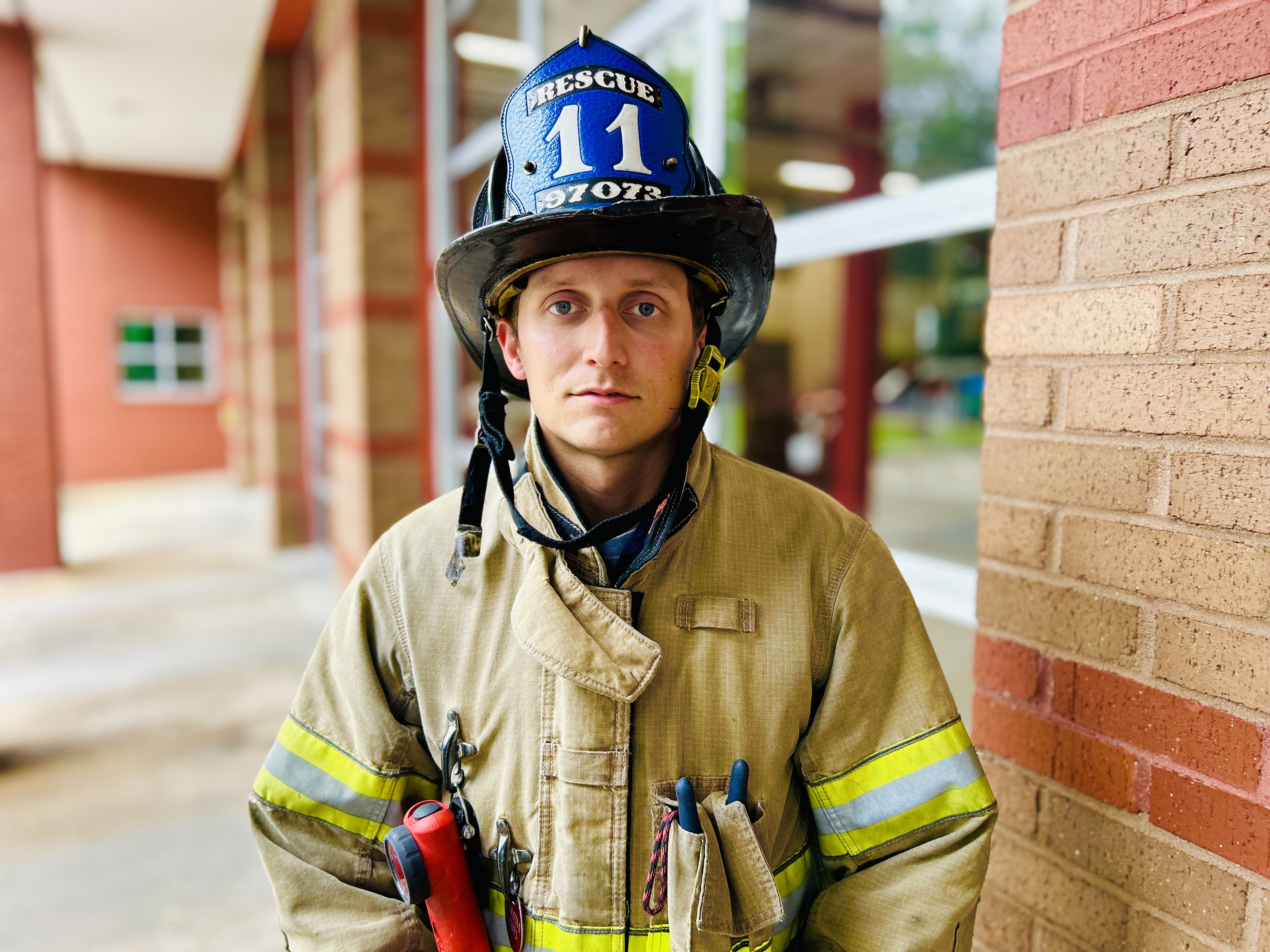 Dressed in turnout gear, Watts pauses outside the bay doors of Rescue 11, reflecting the commitment that earned him the department’s highest honor. 