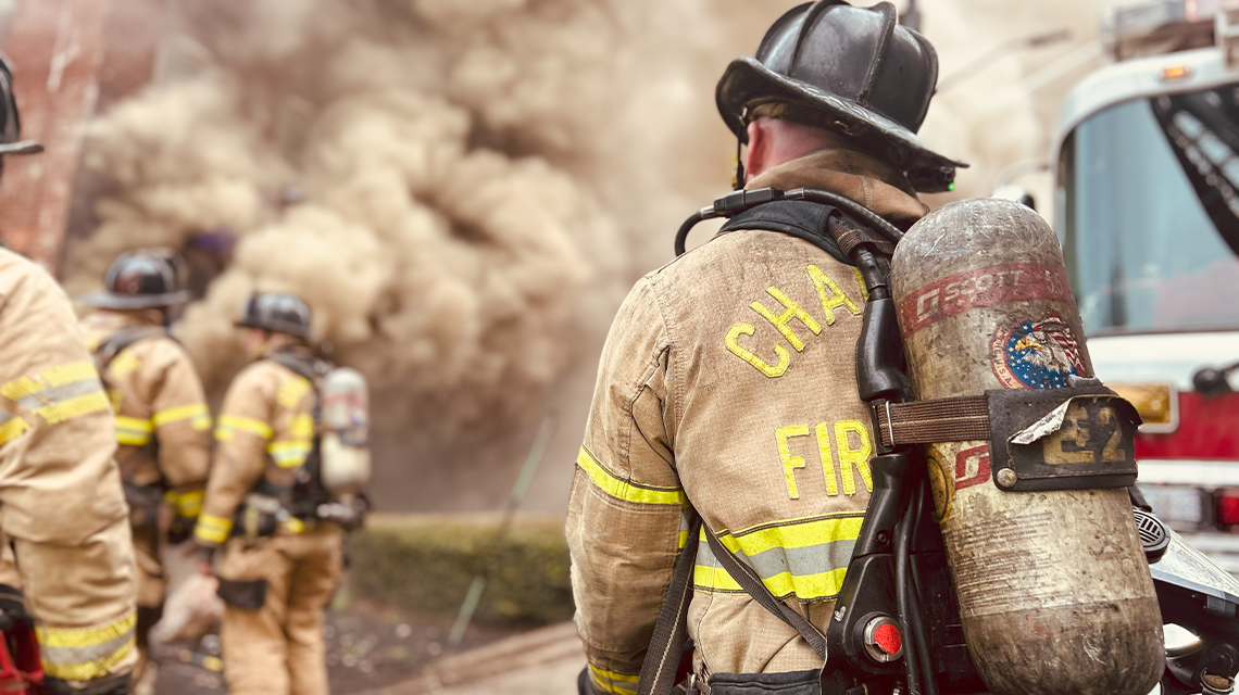  A Charlotte firefighter works a hose line near the front of the building, where heavy smoke pushes from windows and doors. 