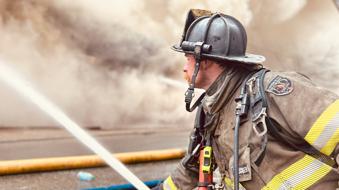 A Charlotte firefighter moves into position with a charged hose line during the East Morehead Street fire.