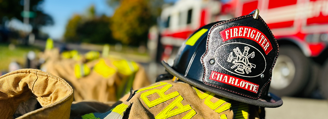 Close up of Charlotte Firefighter helmet with fire truck in the background