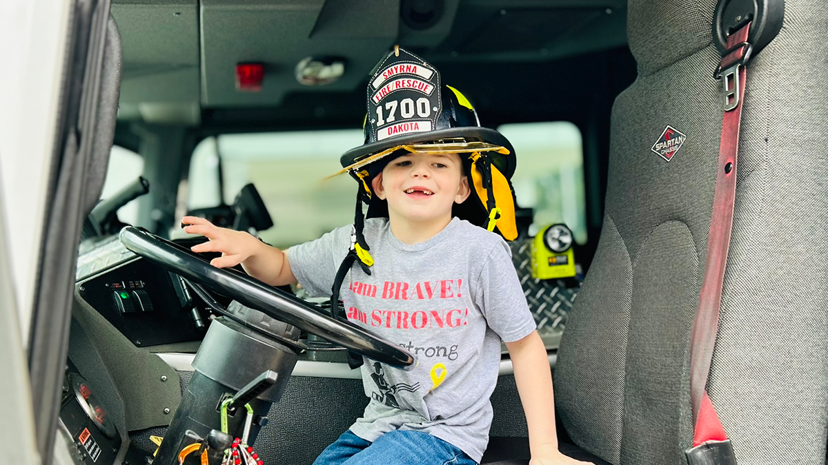 Dakota takes the driver’s seat of Engine 6, joyfully sounding the alarm to celebrate his last day of treatment, a special moment for this brave young fighter.