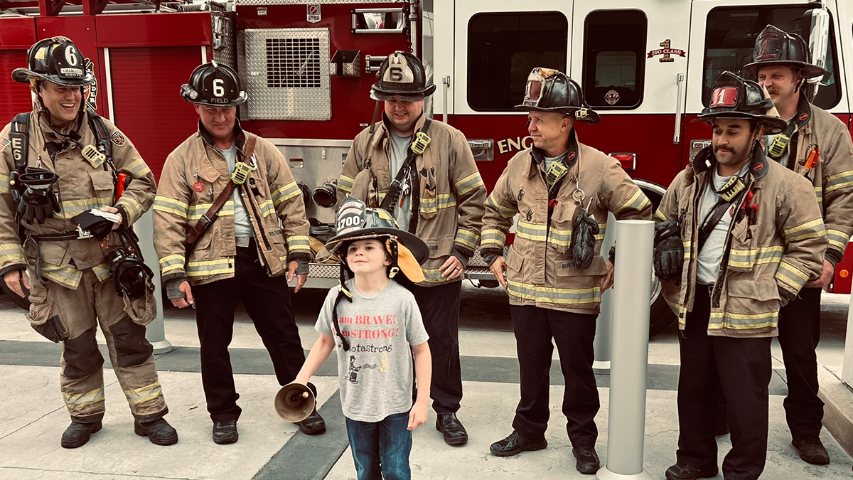 Dakota rings the traditional cancer bell with pride, symbolizing the end of his cancer treatment journey with Charlotte Fire's Engine 6 and Ladder 1 crew..