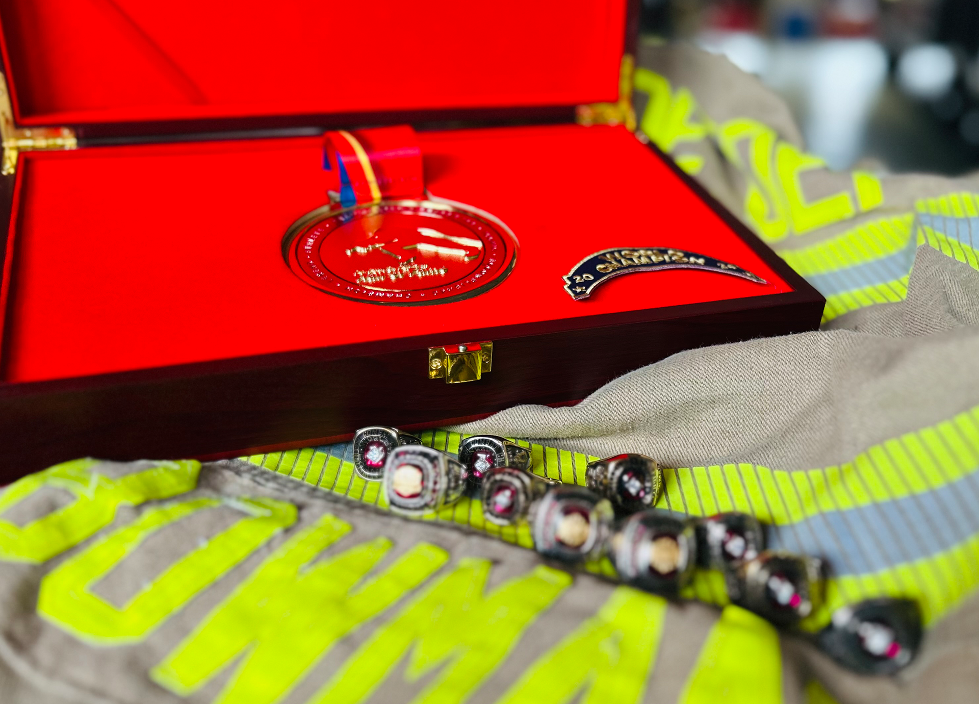 A close-up of Bowman’s Firefighter Challenge Hall of Fame medal and a selection of his championship rings, displayed on the gear that helped earn them.