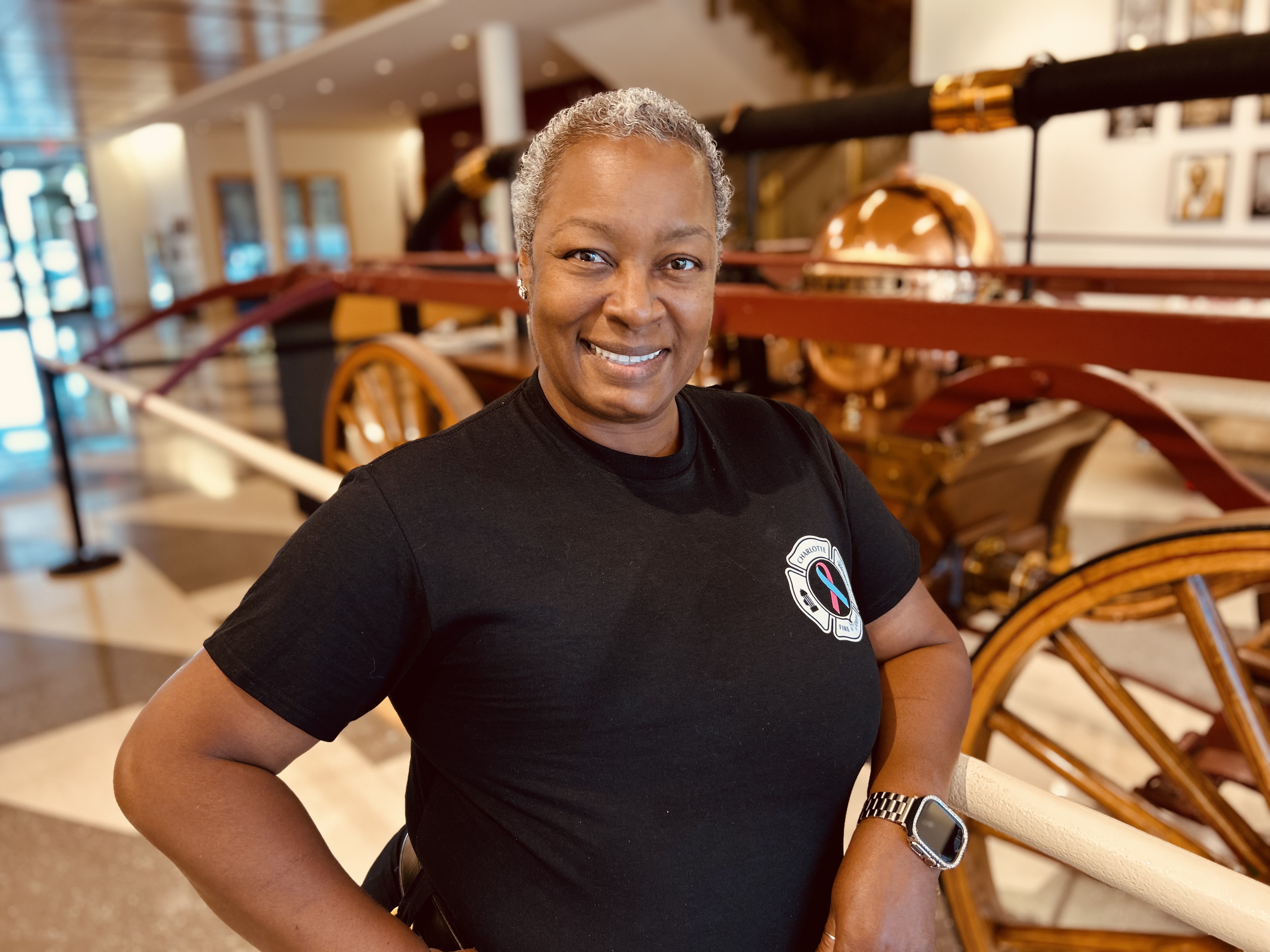 Reynolds stands near a historic fire pumper “The Neptune” — a reminder of both the department’s legacy and the new chapters of courage being written today.