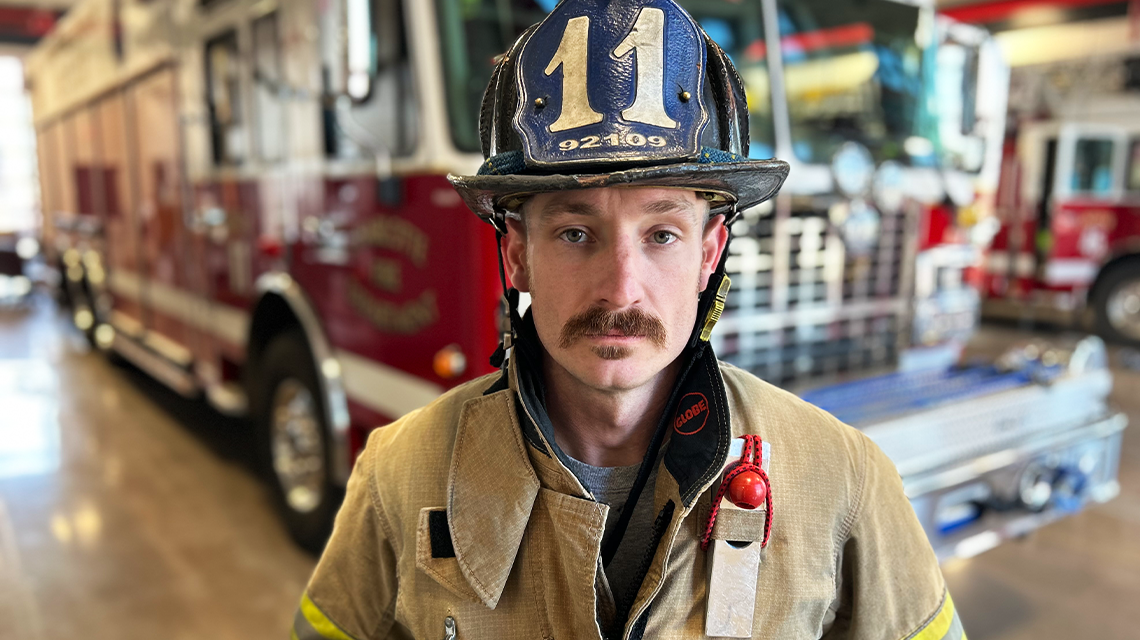  Firefighter Dustin Reynolds stands in turnout gear inside the apparatus bay at Firehouse 45