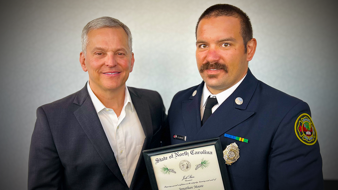 Firefighter Jonathan Moore is awarded The Order of the Long Leaf Pine by Governor Josh Stein. Moore, one of the newest members of Engine 15, showed unwavering determination during the April 29 response.