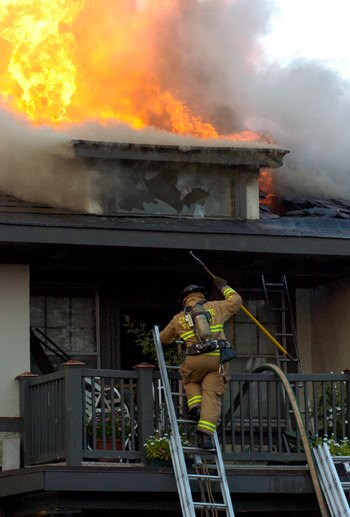firefighter climbing into a burning house