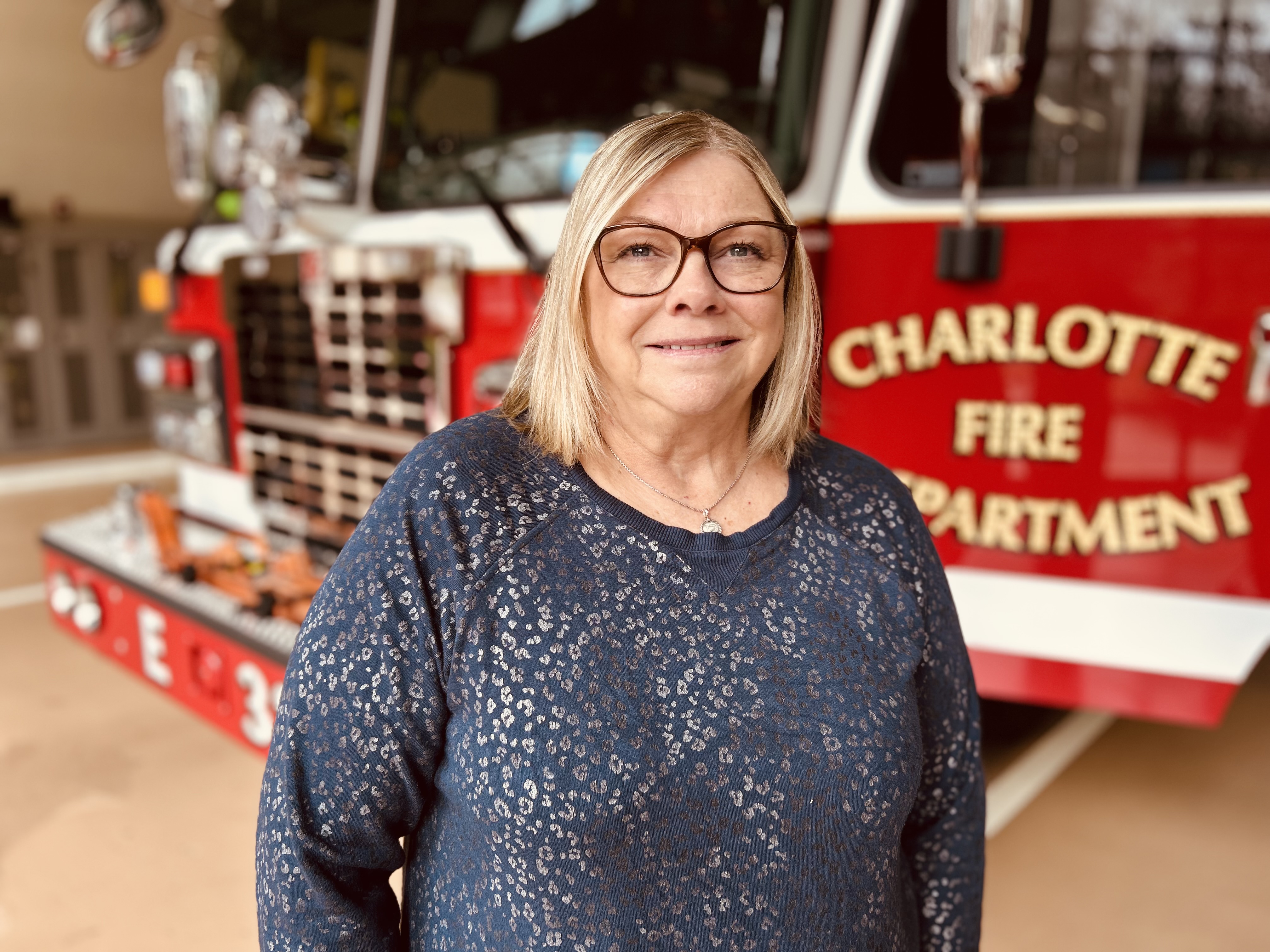 Darlene stands in front of Engine 38, returning to the firehouse with gratitude and a chance to thank the responders who worked to save her life. 
