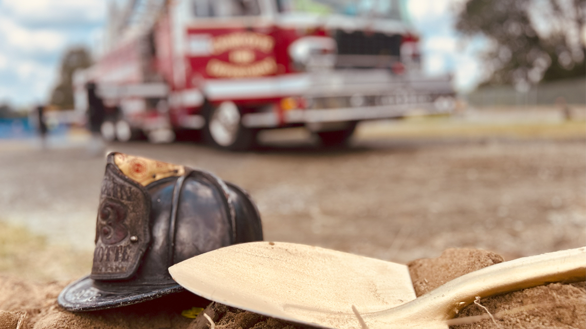 A firefighter’s helmet and ceremonial shovel lie in the dirt near Ladder 33—a quiet tribute to Charlotte Fire’s history and future during the Firehouse 46 groundbreaking.