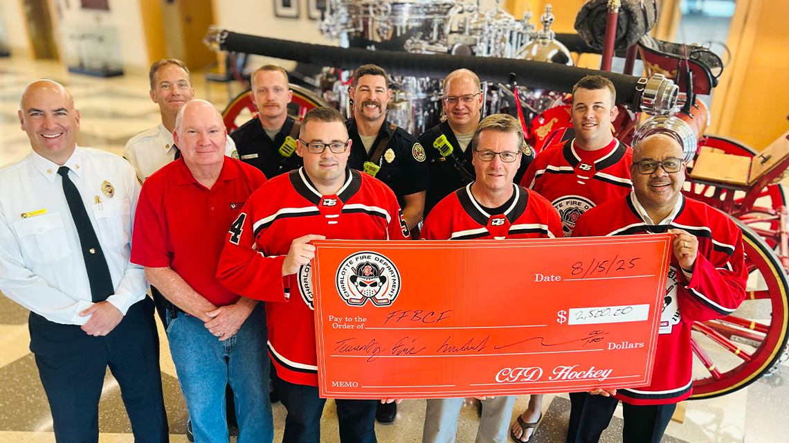 Members of the Charlotte Fire Hockey Team and Charlotte Fire leadership present the donation check to Fire Chief Reginald Johnson in support of the Firefighters’ Burned Children Fund.