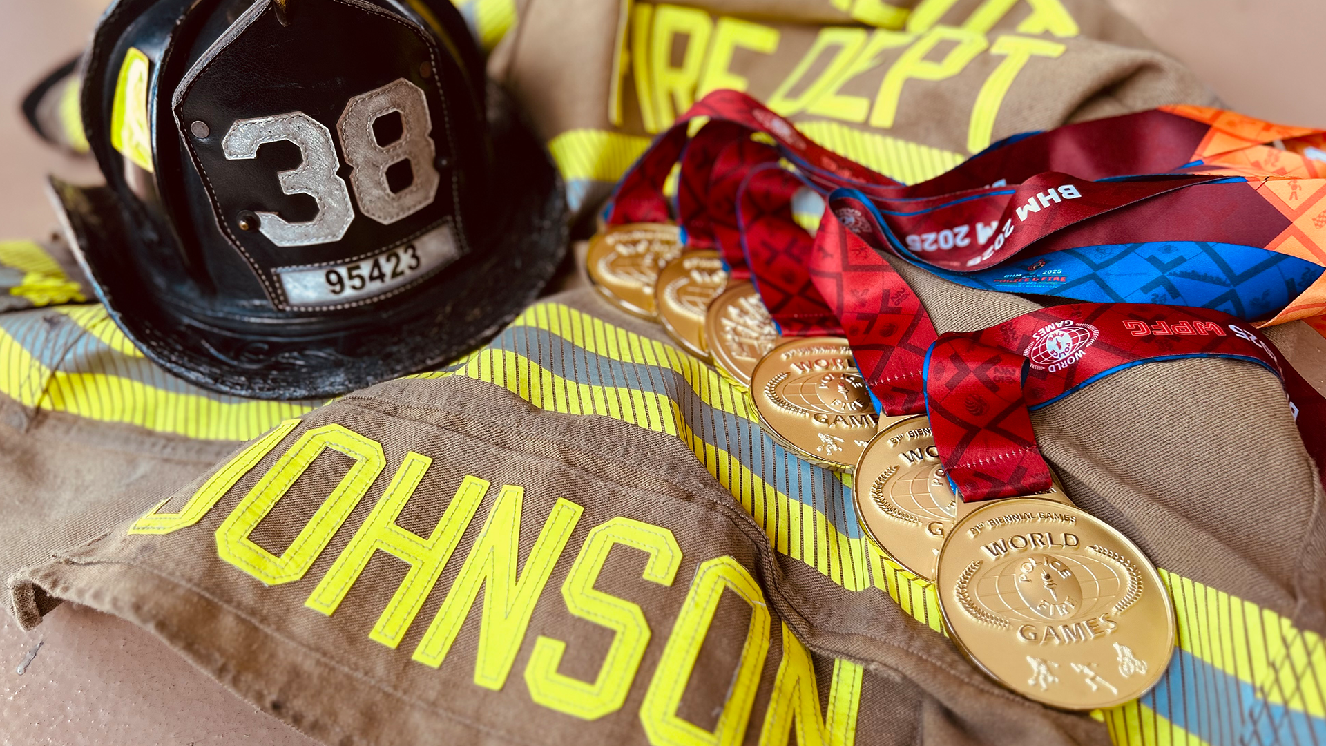 Holly Forbes Johnson’s medals rest alongside her Charlotte Fire turnout gear, representing both her firefighting career and her athletic success. 