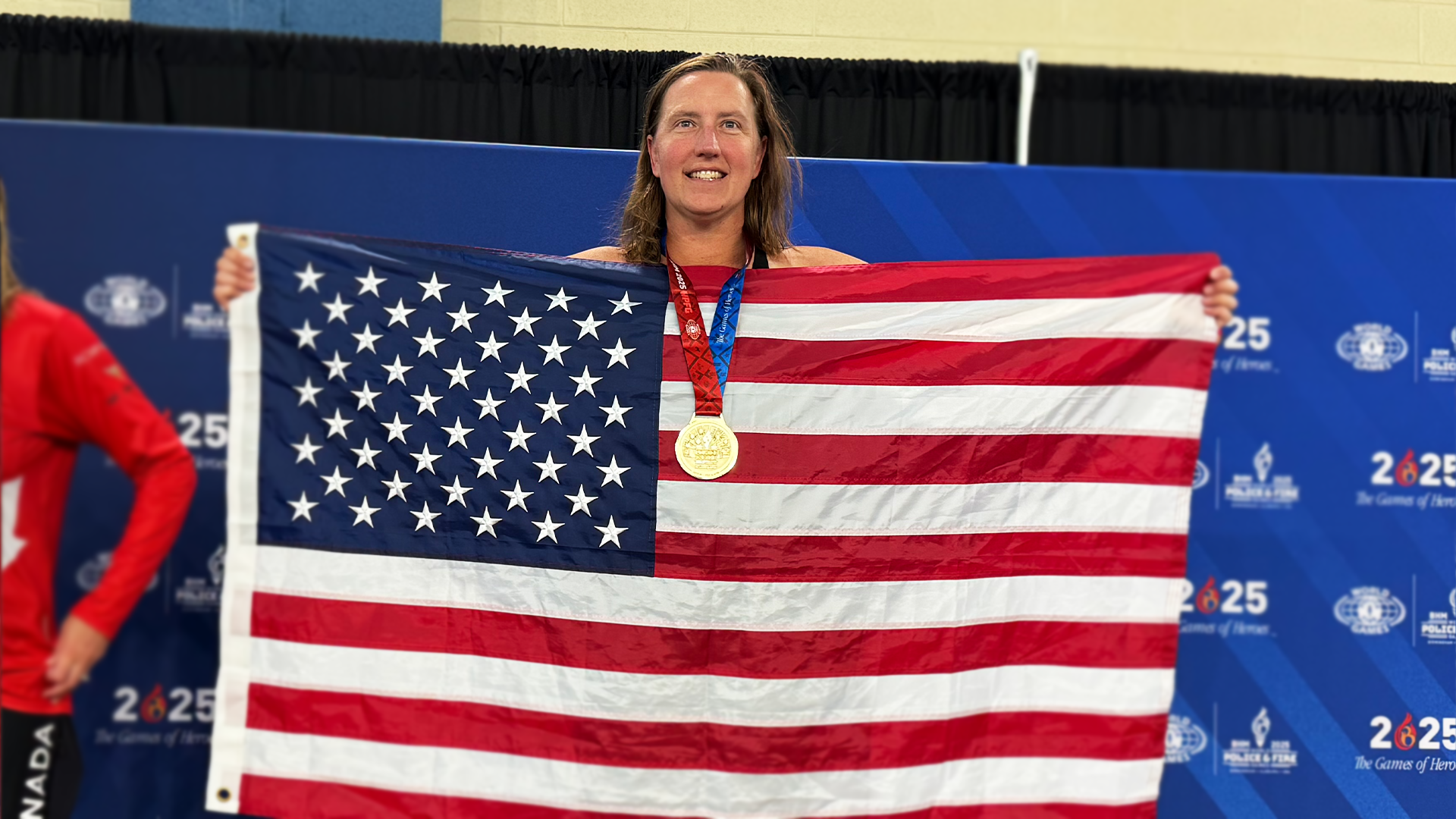 Johnson holds the American flag after capturing gold in her swimming events at the World Police & Fire Games. 