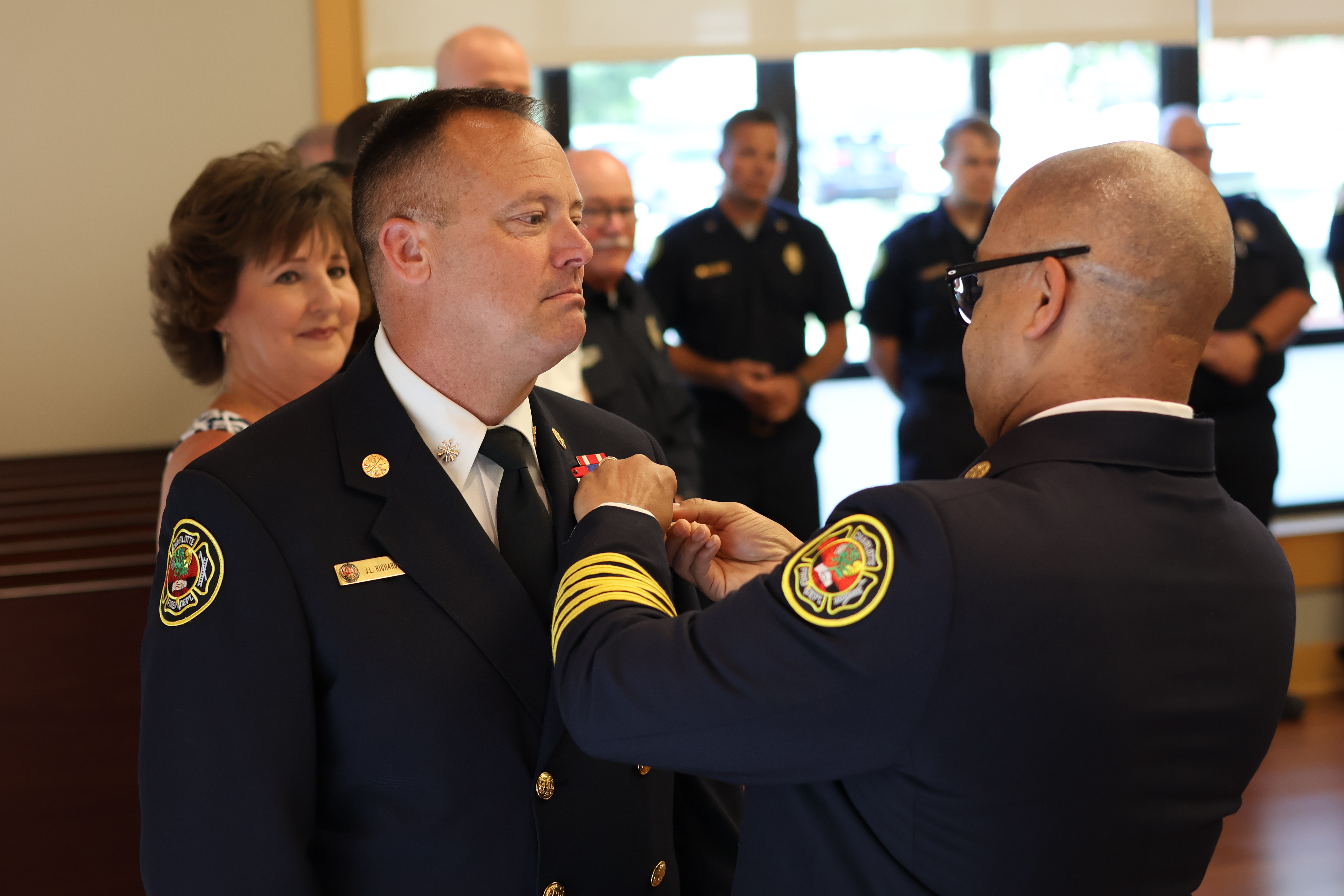 Fire Chief Reginald Johnson pins the Deputy Chief insignia on Richardson during the promotion ceremony.