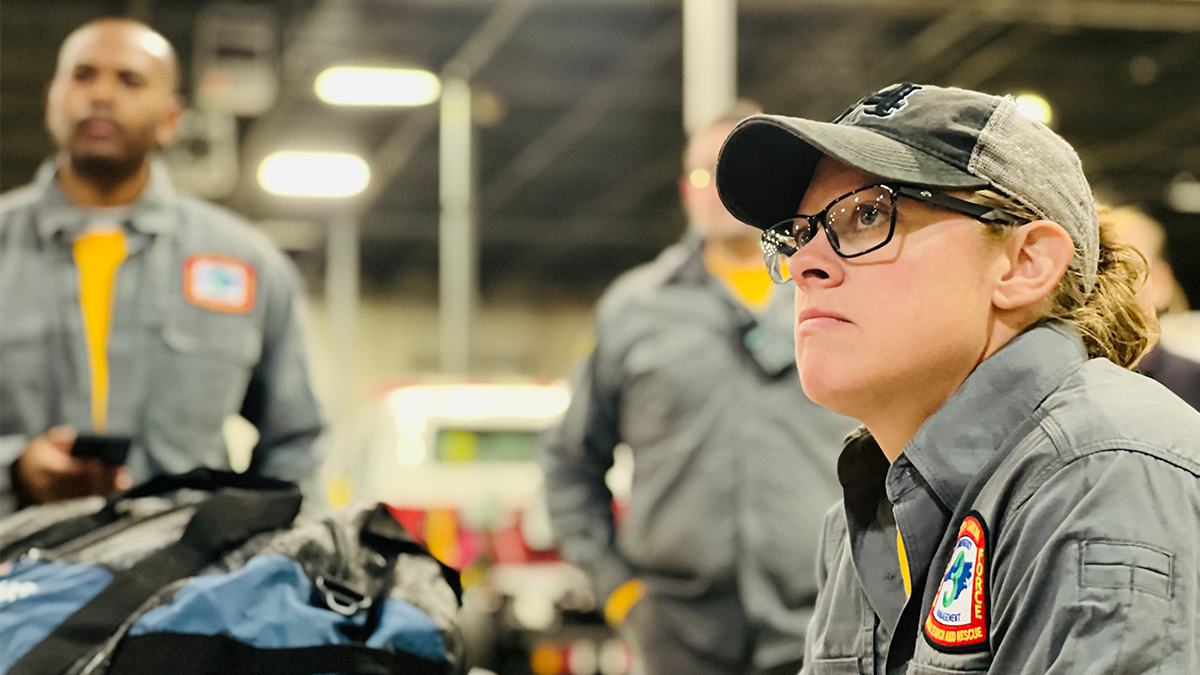 Charlotte Firefighter Tawni Chambers listens intently during a pre-deployment briefing, preparing to assist communities in Kentucky facing devastating flood conditions.