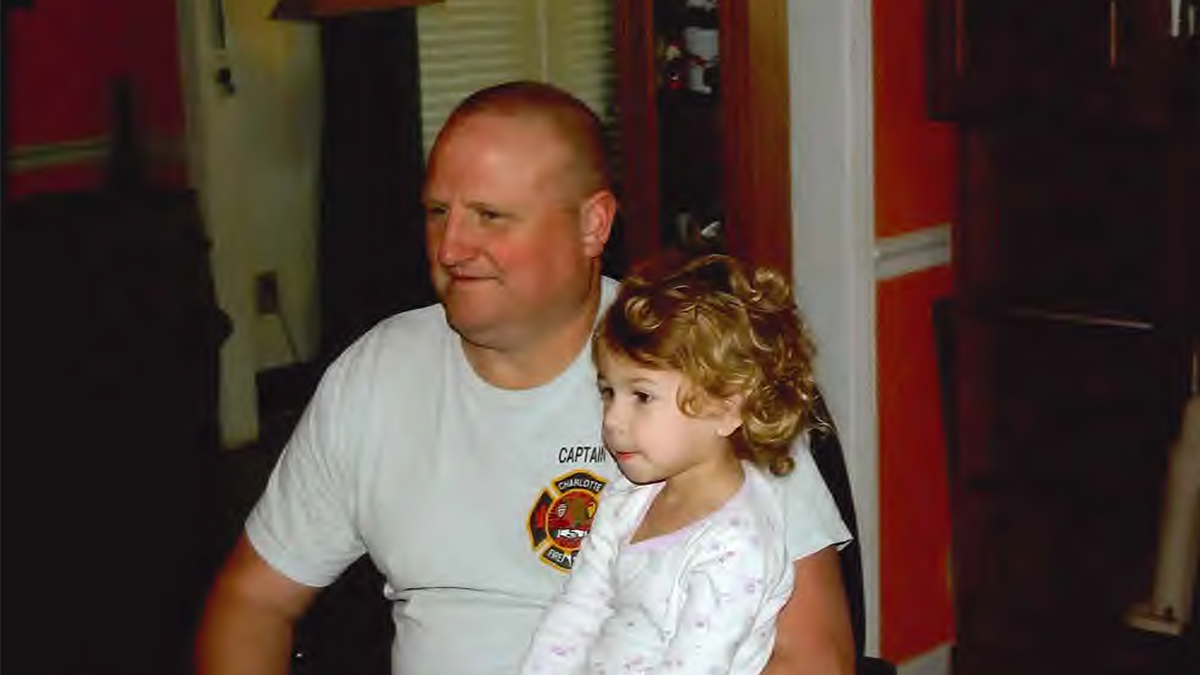 Brian Davenport, wearing his Charlotte Fire Captain shirt, shares a quiet moment with Kilah. Their bond was unbreakable, built on love, laughter, and cherished time together.