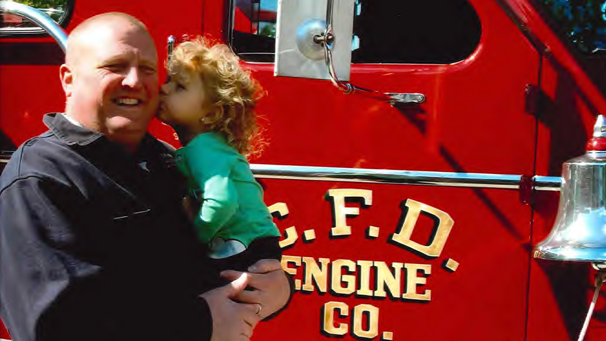 A special moment between Kilah and her grandfather, Brian Davenport, in front of a Charlotte Fire engine—a symbol of his lifelong commitment to service and family.