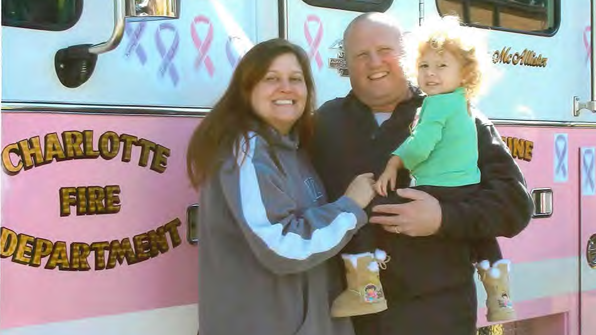 Brian and his wife, Leslie, stand together with Kilah in front of a Charlotte Fire truck, bonded by love, strength, and their shared mission to honor Kilah’s legacy.