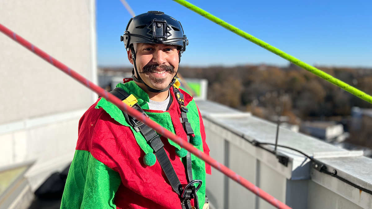 Firefighter Hector Rivera, dressed as an elf, prepares to bring smiles to young patients with a cheerful holiday rappel.