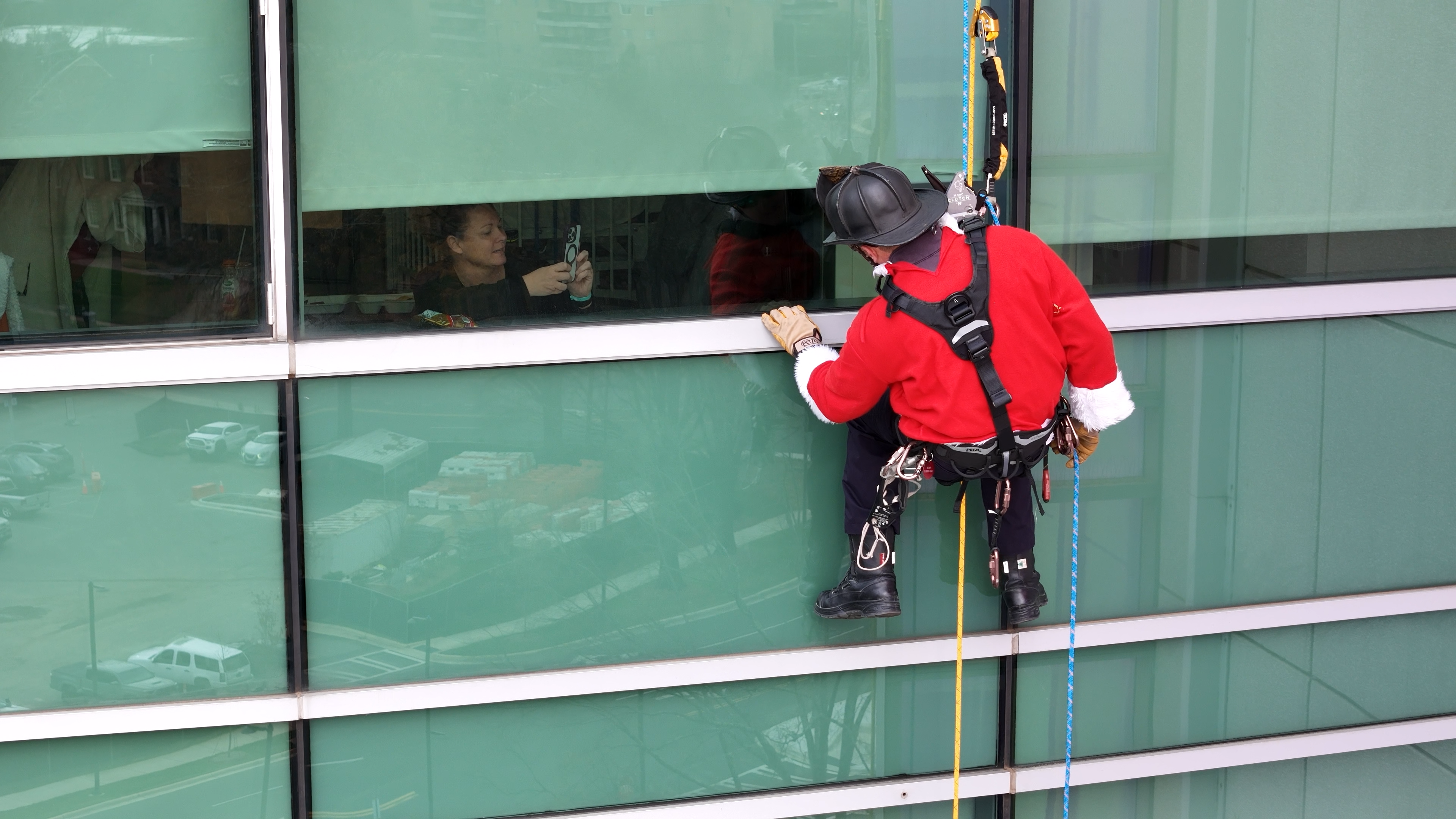A Charlotte Firefighter in full Santa gear taps gently on a patient’s window from high above, creating a moment of magic that won’t soon be forgotten. 