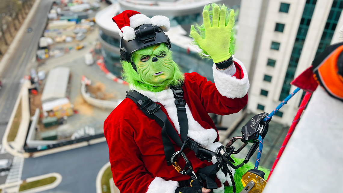 Not even the Grinch could resist this view. One of Charlotte Fire’s festive volunteers gives a wave mid-rappel, proving even green-hearted guests can spread joy. 