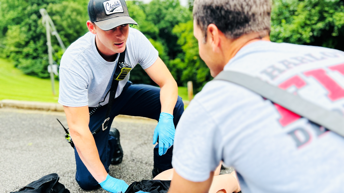 A firefighter kneels beside a simulated victim, focused on rapid assessment and life-saving intervention—a critical part of Charlotte Fire’s commitment to readiness. 
