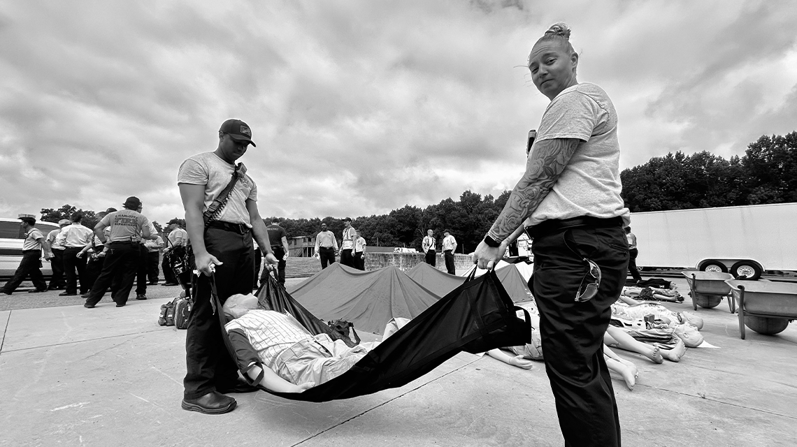 Firefighters carry a victim in a rescue drag tarp, a tactic used when time and safety demand quick evacuation from hazardous areas in a mass casualty situation.