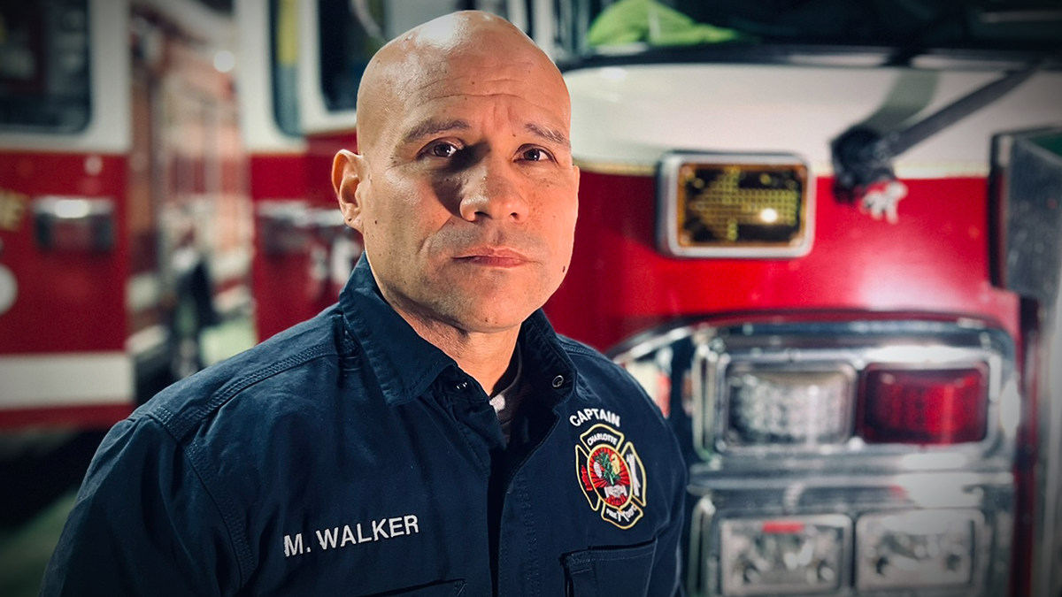 Standing in front of Ladder 16 at Charlotte Firehouse 16, Captain Matthew Walker reflects on his 18-year career and personal journey through firefighting and cancer survival.