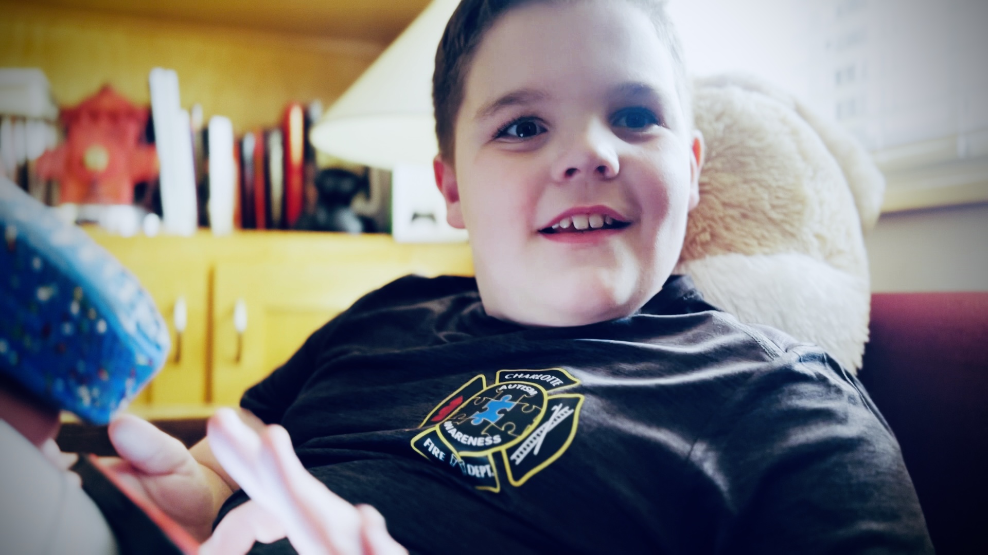 Benjamin Powell relaxes at the firehouse, wearing a Charlotte Fire autism acceptance shirt