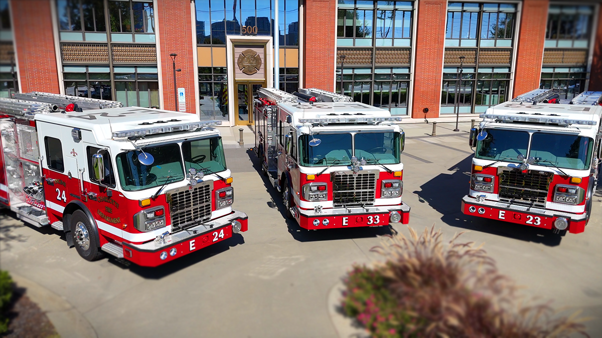 The latest additions to Charlotte Fire's fleet, Engines 24, 33, and 23, housed and ready for action in front of the iconic headquarters building.