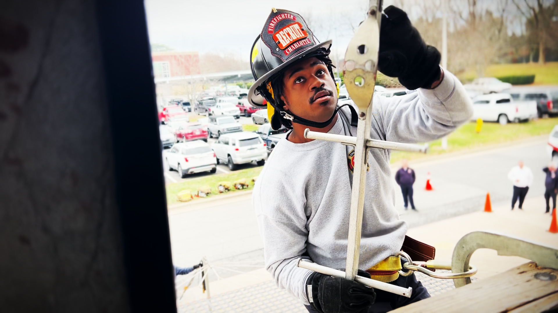 Charlotte Fire Recruit Jaden Camp focuses on lining up the hook and rung, learning the precision required to climb safely on the pompier ladder. 