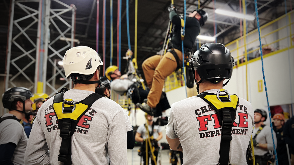 Firefighter Clayton Llewellyn demonstrates advanced rope rescue techniques while students observe and prepare to apply the skills during their training.