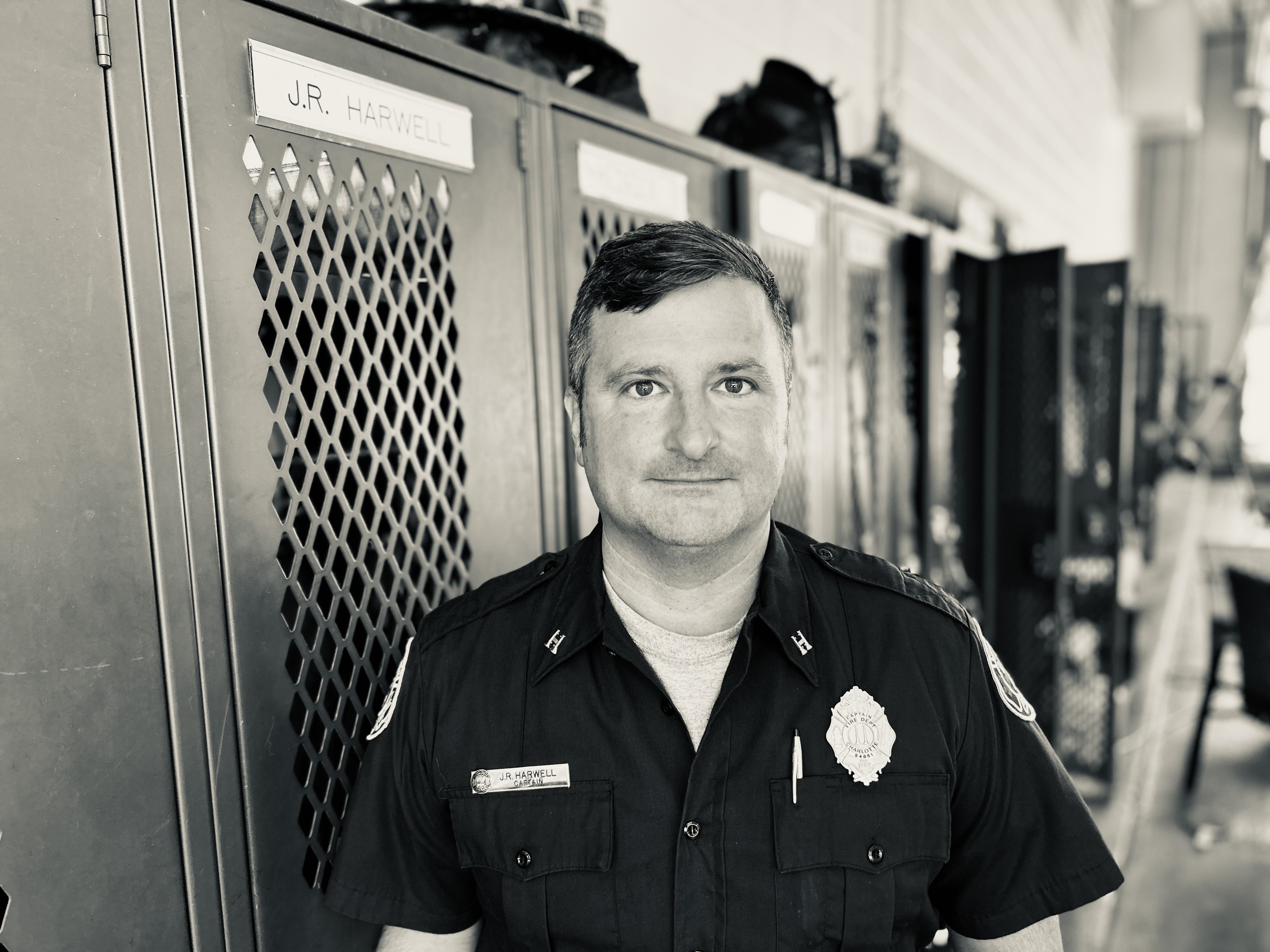 Capt. Harwell stands beside his locker at Firehouse 31, a place that holds both the weight of daily duty and the quiet strength of his personal story.