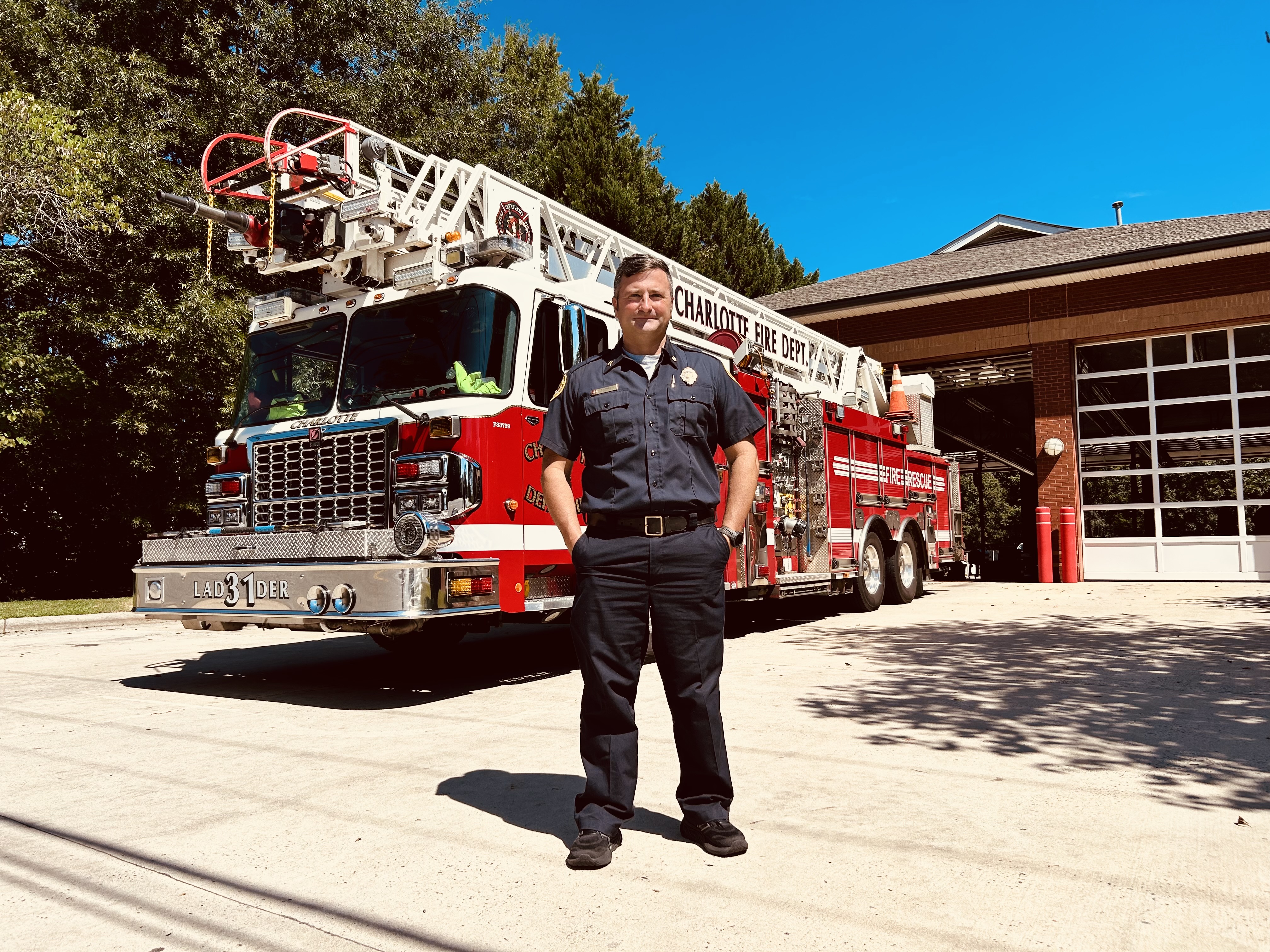 Capt. Harwell outside Firehouse 31 with Ladder 31 behind him, showing his resilience as both a firefighter and a survivor.