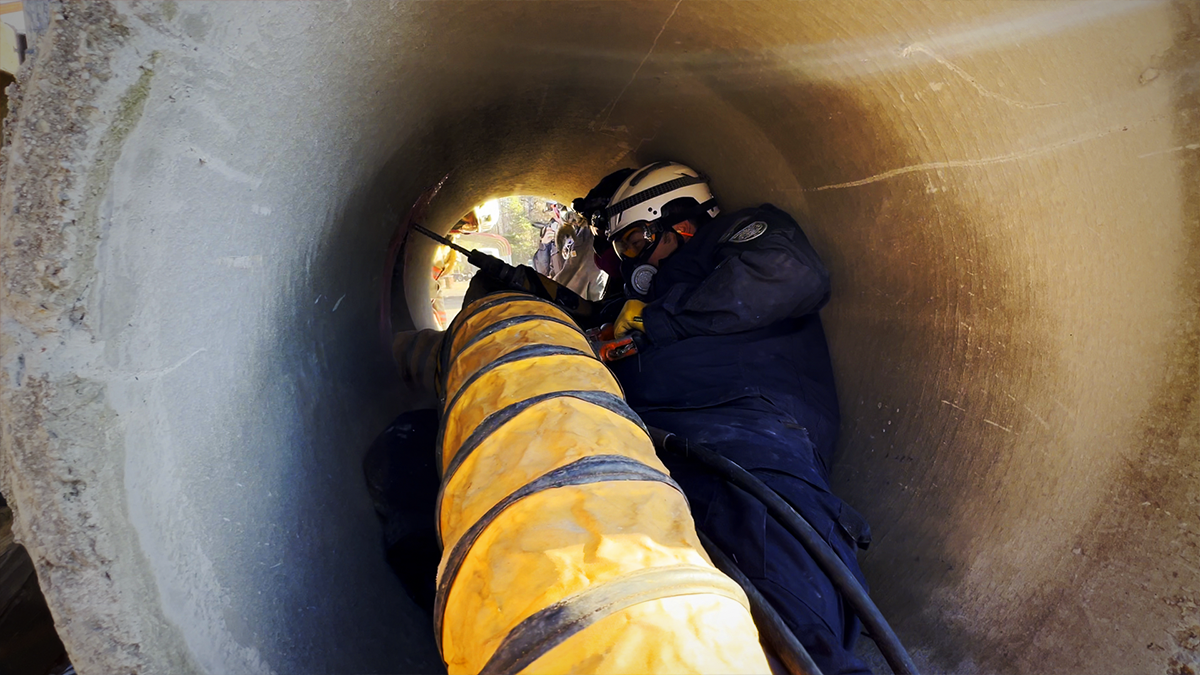 irefighters maneuvers through a confined space, simulating a real-world rescue scenario. The training builds essential skills for navigating collapsed structures to reach trapped victims.