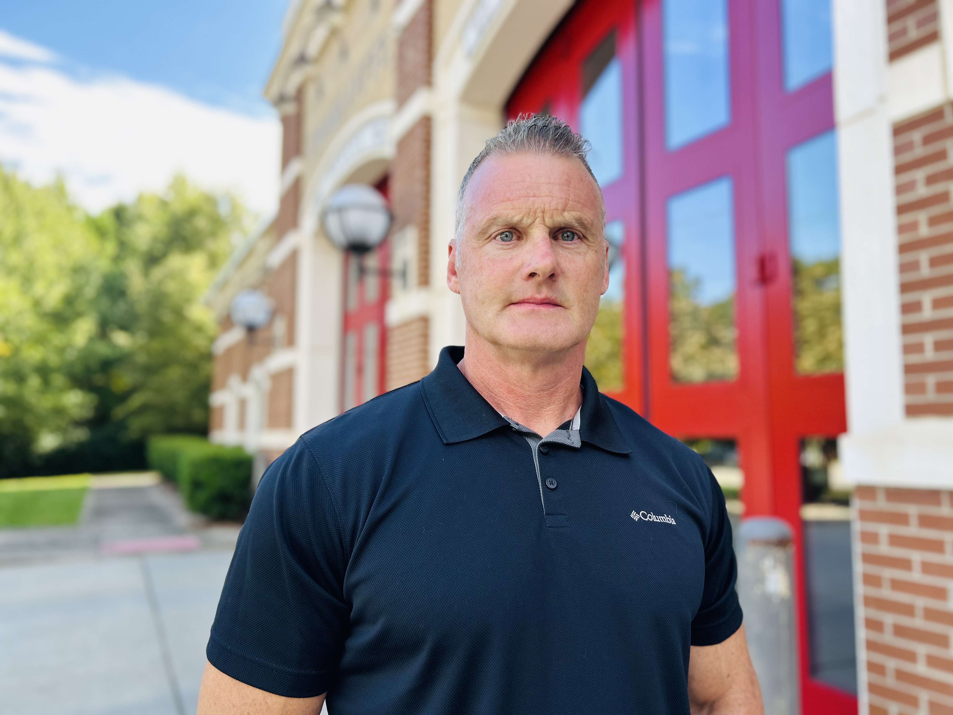 Walker in front of the bright red bay doors, a striking image of strength and resilience after a career of service. 