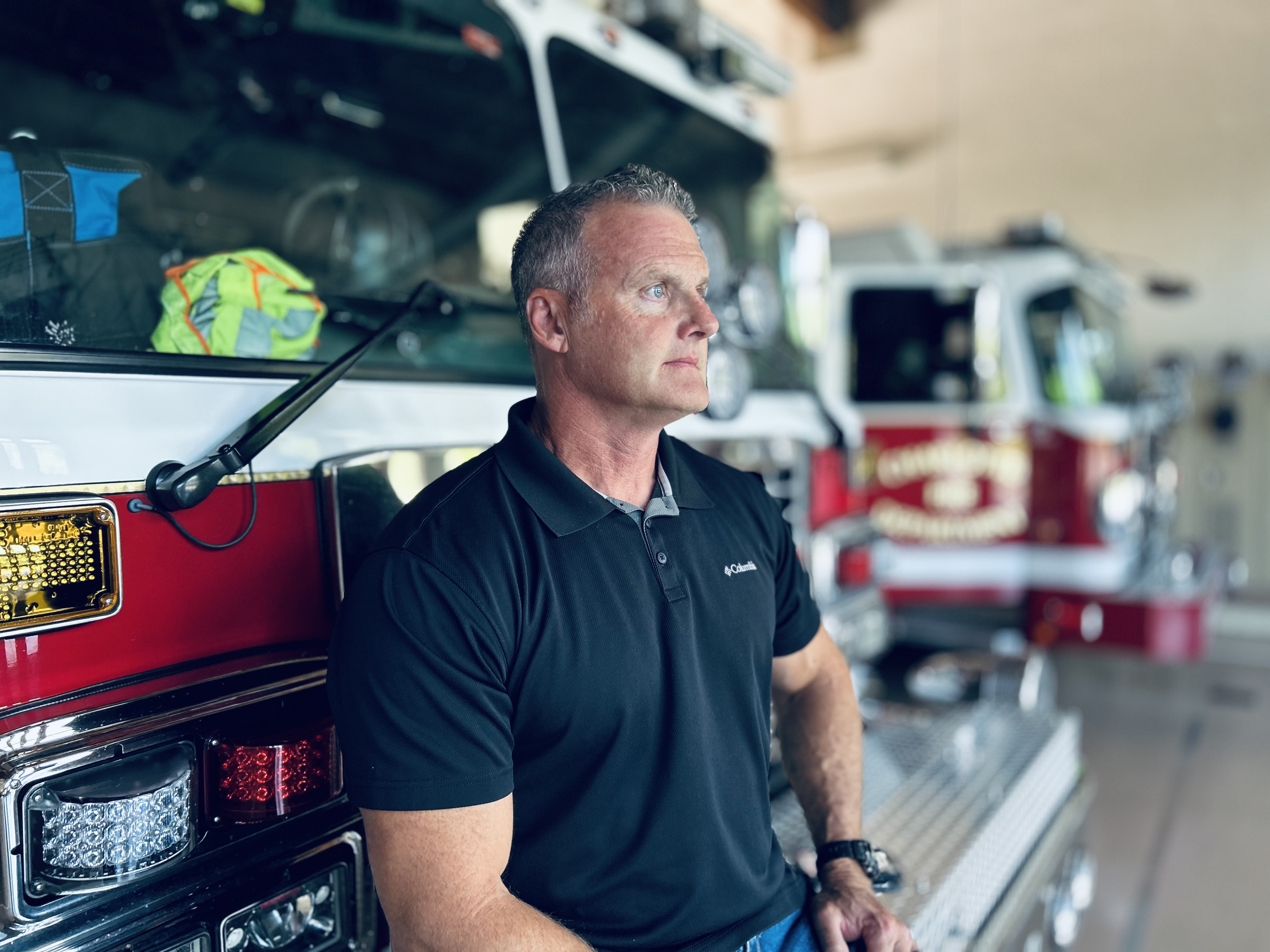 Walker leans against a fire truck, looking ahead with focus and determination about life beyond firefighting and cancer 
