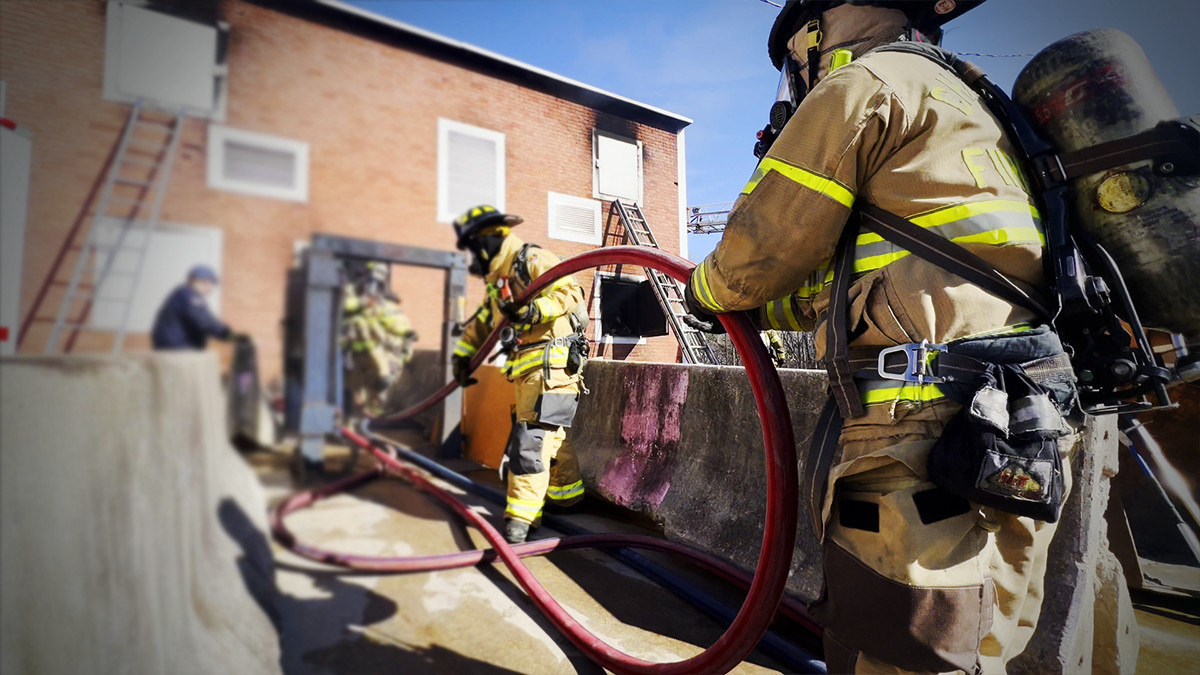 Firefighters practice stretching attack lines into a simulated residential structure, honing their speed and precision during Charlotte Fire’s winter training session.