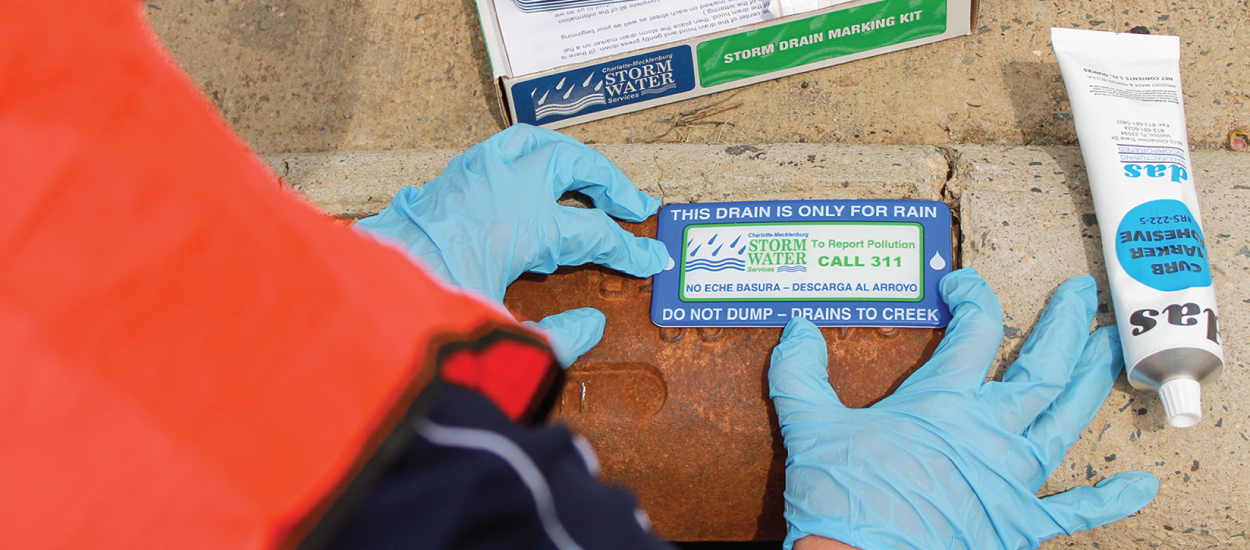 Volunteer marking a storm drain with a marker.